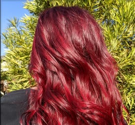 A client showcasing their hair after using a vibrantly pigmented AURA Masque