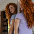 Woman with long, red, auburn curly hair looking in the mirror thumbnail